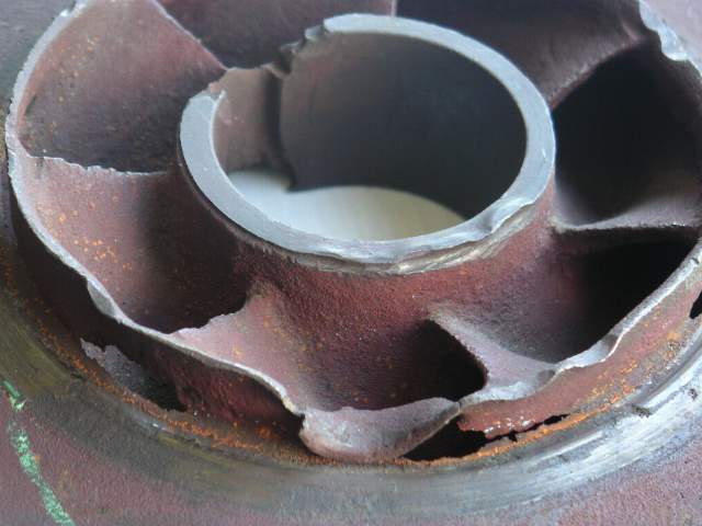 A centrifugal pump impeller destroyed by cavitation erosion, showing pitted, sponge-like metal surfaces
