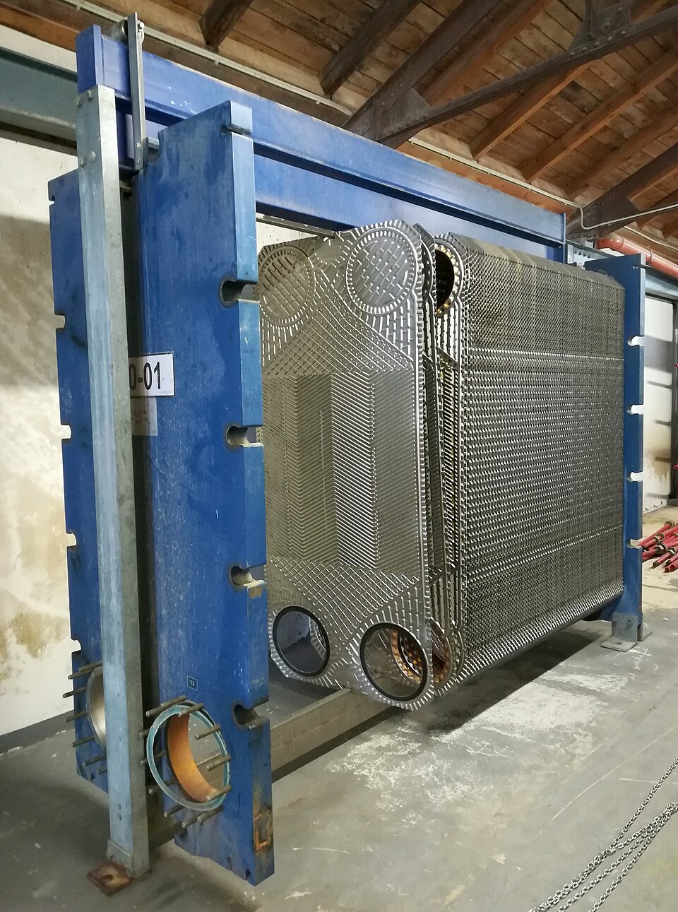 A dismantled plate heat exchanger showing the stacked corrugated metal plates hot and cold streams flow between