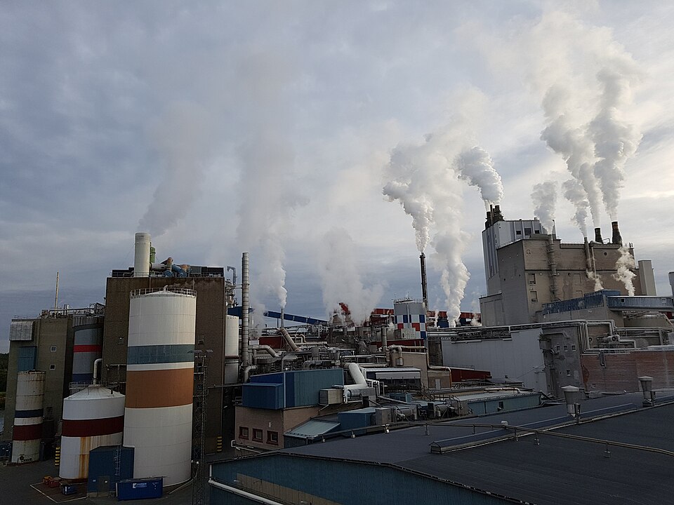 An industrial factory exterior with a smoking chimney